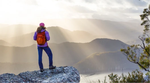 a woman standing on a rock looking out over a valley